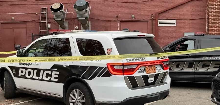 Police investigate death in downtown Durham; officers gather behind row of businesses
