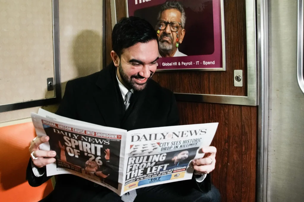 French tourists didn’t believe the young guy on the subway was New York City’s new mayor, so he held up the newspaper to prove it